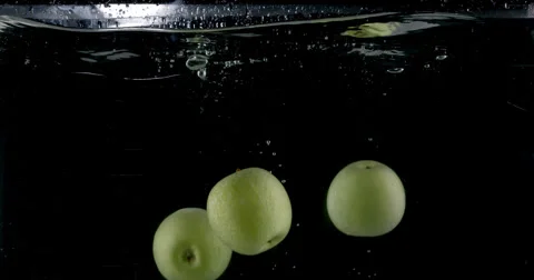 Slow-motion shot of a fresh green apple being thrown into water. Stock Footage 300488208