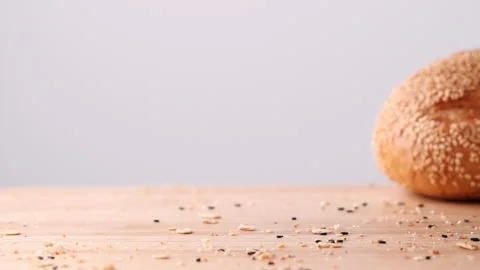 Slow motion shot fresh hamburger bun with sesame seeds falling Vídeo Stock 165347345