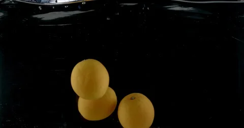 Slow-motion shot of a fresh orange being thrown into water. Stock Footage 300497196
