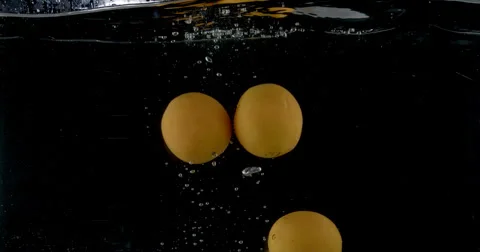 Slow-motion shot of a fresh orange being thrown into water. Stock Footage 300502570
