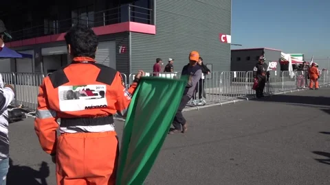 Slow motion shot of a go-karting marshall waving the green flag to race Stock Footage 238010814
