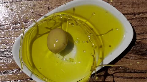 Slow Motion Shot of Green Olive Falling into Fresh Olive Oil 動画素材 138751853