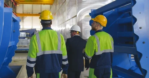 Slow motion shot group of engineers and foremen in uniform walk fast through Stock Footage 121099496