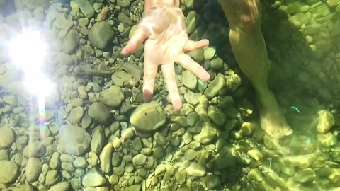 Slow-motion shot of a hand moving in dancing circles above and under water Stock Footage 248380866