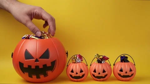 Slow motion shot of hand picking candy from halloween pumpkin head basket Stock Footage 209332884
