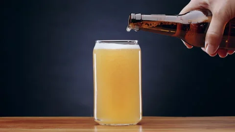 Slow motion shot of hand pouring hefeweizen wheat beer into beer glass on bar Stock Footage 134521733