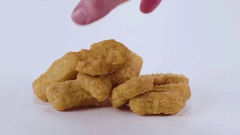 Slow motion shot of a hand pulling chicken tenders off of a white cyc Stock Footage 70678697