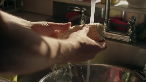 Slow motion shot of hands cleaning a fresh ear of corn in the sink Video stock 153299428