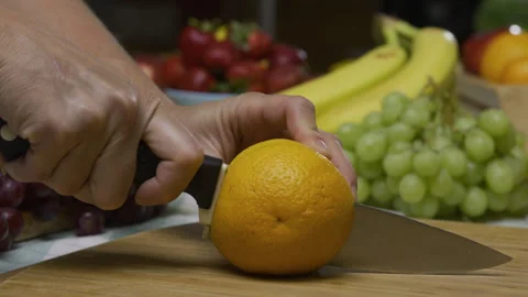Slow motion shot of knife cutting through delicious, juicy orange on cutting Stock Footage 341222645