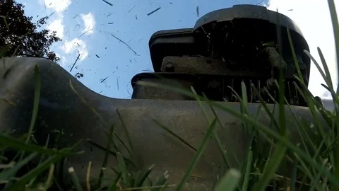 Slow motion shot of a lawn mower being pushed over a camera on the grass Stock Footage 77079979
