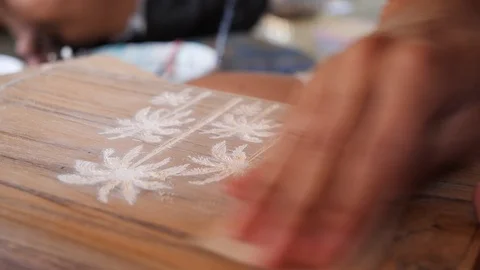 Slow motion shot of local man sanding wooden board with carved palm trees, Bali Stock Footage 140253370