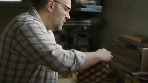 Slow motion shot of man cleaning wood with cube pattern in workshop / Provo, Stock Footage 89186986