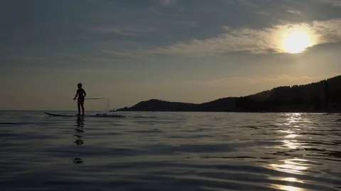 Slow motion shot of a man floating on a board at sunset on the beach 库存影片 80593309