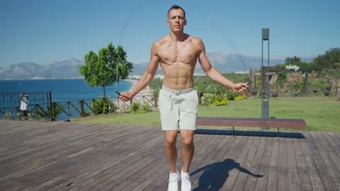 Slow motion shot of a man having cardio training outdoors and throwing skipping Video stock 198684376