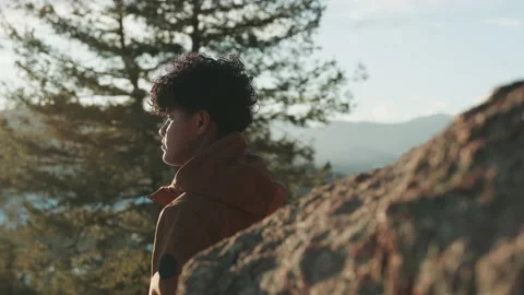 Slow motion shot of man looking into the sunset in a forest with trees with the Vidéo 234379868