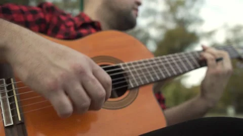 Slow motion shot of a man playing an acoustic guitar at park Stock-Footage 139294819