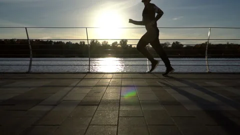 Slow motion shot of man running on a river promenade in a fall sunset light. Stock Footage 254471488