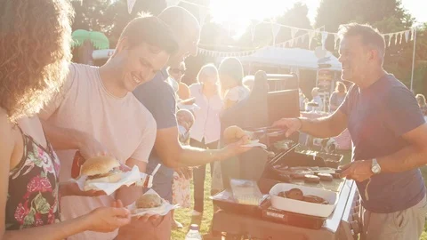 Slow Motion Shot Of Man Serving On Barbeque Stall At Summer Garden Fete Vídeos de archivo 99743432