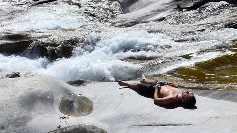 Slow motion shot of a man sleeping on the rocky banks of an alpine stream 動画素材 114178485