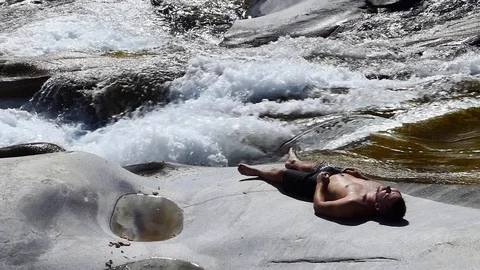 Slow motion shot of a man sleeping on the rocky banks of an alpine stream 動画素材 114178519