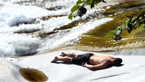 Slow motion shot of a man sleeping on the rocky banks of an alpine stream Stock-Footage 114178553