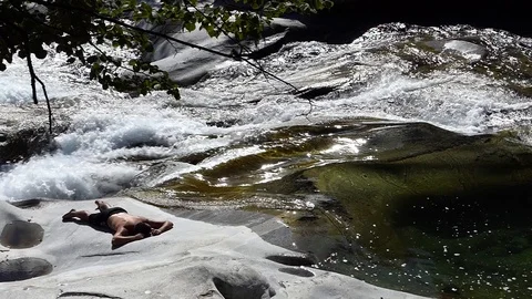 Slow motion shot of a man sleeping on the rocky banks of an alpine stream 動画素材 114178573
