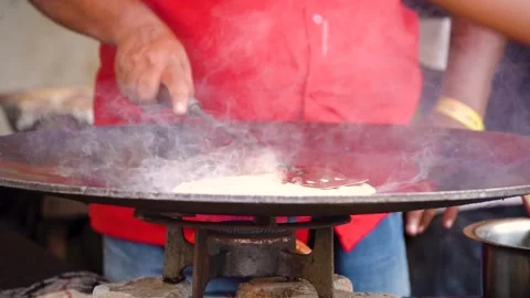 Slow motion shot of man using steel spatula to make paratha flat bread on huge Vídeo Stock 245550347