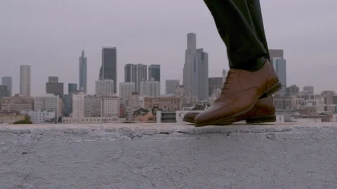 Slow motion shot of man walking across ledge wearing dress shoes Stock Footage 127193634
