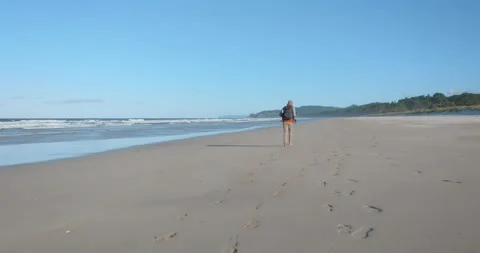 Slow-motion shot of a man walking alone on a remote beach Stock-Footage 279859077