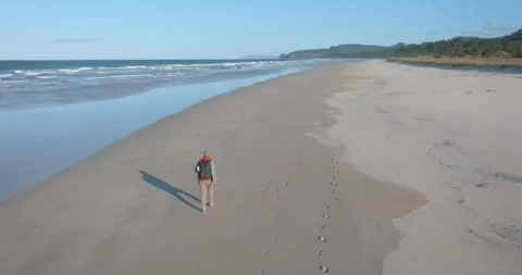 Slow-motion shot of a man walking alone on a remote beach Stock-Footage 279859132