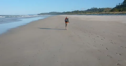 Slow-motion shot of a man walking alone on a remote beach Stock-Footage 279859153