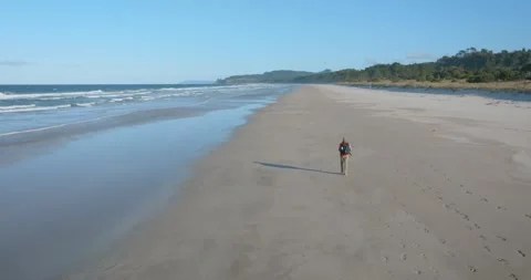 Slow-motion shot of a man walking alone on a remote beach Stock-Footage 279859232