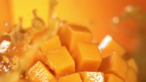 Slow Motion Shot of Mango Juice Splashing through Mango Cube Slices 库存影片 193088677