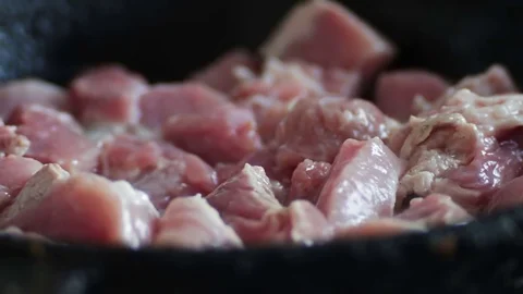 Slow motion shot of a meat cooking in the frying pan. Man is stirring it with a Stock Footage