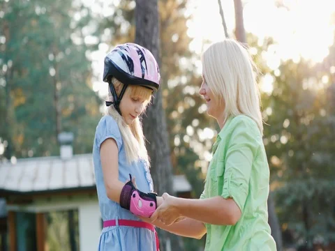 Slow motion shot: Mom dresses daughters of elbow pads for cycling or roller Stock Footage 79959441