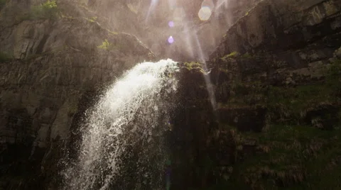Slow motion shot moving towards waterfall flowing off rocky ledge Stock Footage 52498627