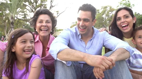 Slow Motion Shot Of Multi Generation Family Sitting In Park Stock Footage