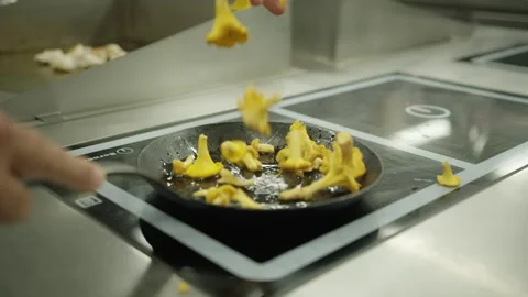 Slow motion shot of mushrooms falling into a frying pan in a fine dining kitchen Stock Footage 328833834