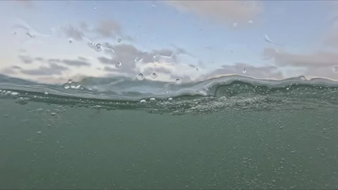 Slow motion shot of ocean surface showing split waterline with bubbles, foa.. Video stock 316888979