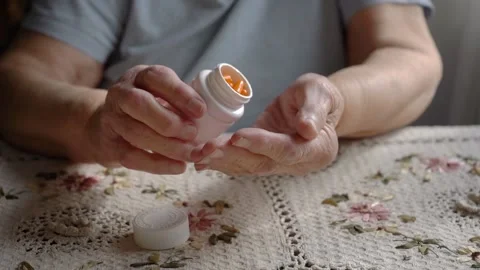 Slow motion shot of the old lady take orange pills from the white pillbox Stock Footage 134022343