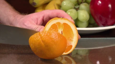 Slow motion shot of an orange being cut on a cutting board. Stock Footage 34662497
