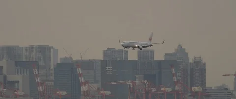 Slow motion shot of plane preparing to land in airport with city in back, Tokyo Stock Footage 136130761