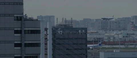 Slow motion shot of plane preparing to land in airport with city in back, Tokyo Stock Footage 136131477