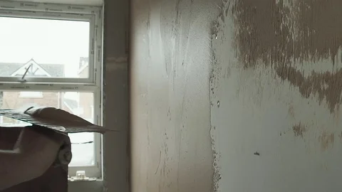 Slow motion shot of a plasterer adding smooth plaster to a plasterboard wall Video stock 77745924