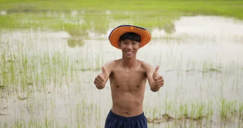 Slow motion shot, Portrait of young farmer without shirt wearing hat showing  Stockbeeldmateriaal 202055972