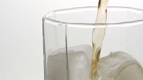 Slow Motion Shot of Pouring Ice Tea or whisky into Glass with Ice Stock Footage 147356111