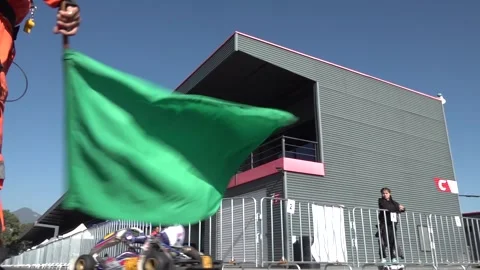 Slow motion shot of a race marshall waving the green flag to race Stock Footage 238010589