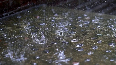 Slow motion shot of raindrops falling to the ground, resulting in splashes of Video stock 97866171