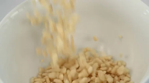 Slow motion shot of rice breakfast cereal falling into white bowl Stock Footage 73342318