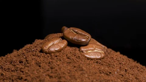 Slow motion shot of rotating coffee beans on the pile of ground coffee Vídeos de archivo 128671345